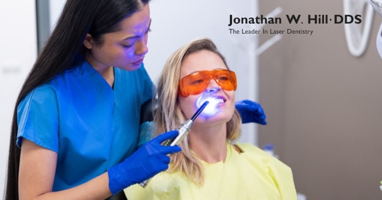 female dentist makes a teeth whitening laser procedure in the clinic